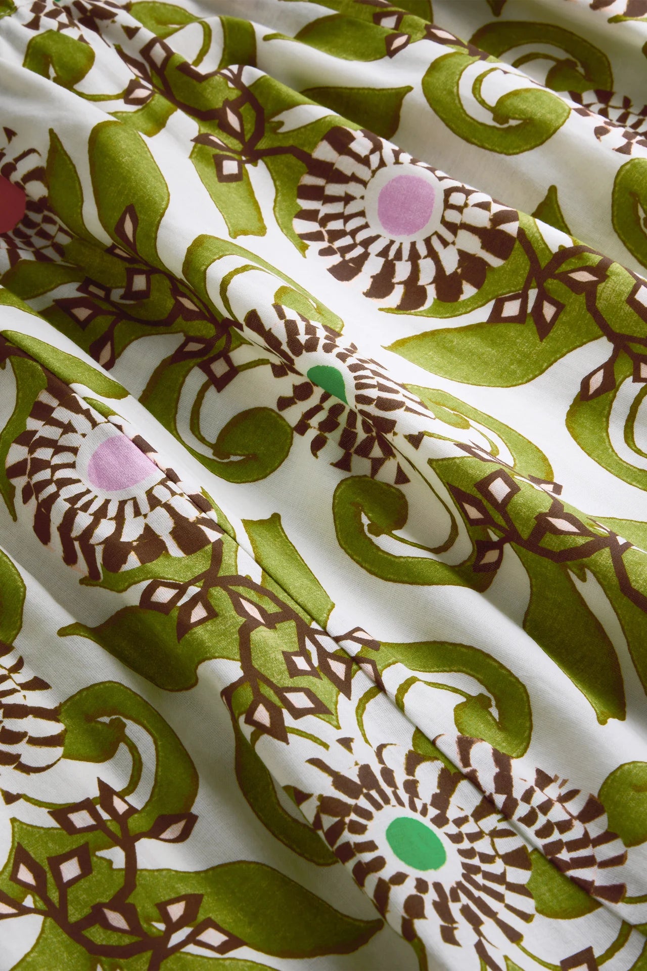 Close-up of fabric with a green and brown floral pattern on a white background