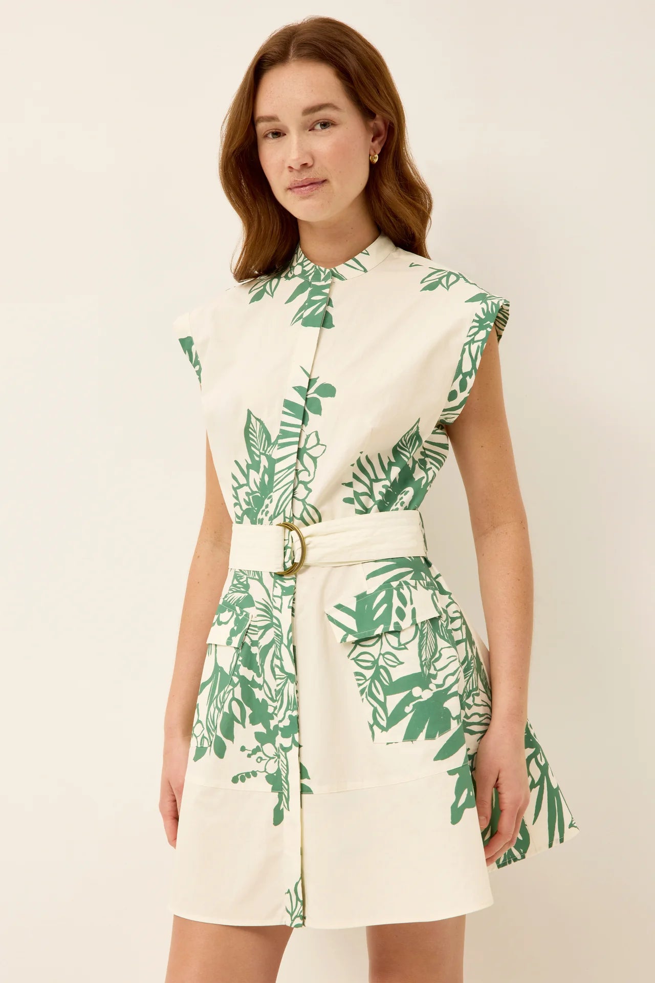 Woman wearing a white dress with green leaf pattern on a plain background