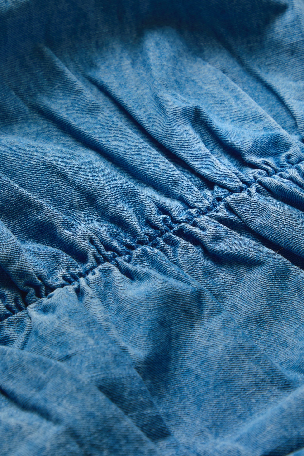 Close-up of a blue textured fabric with gathered elastic stitching.