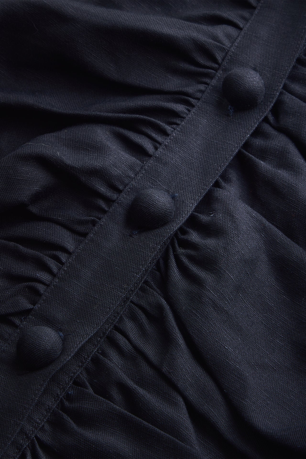 Close-up of a black dress with buttons and ruched details