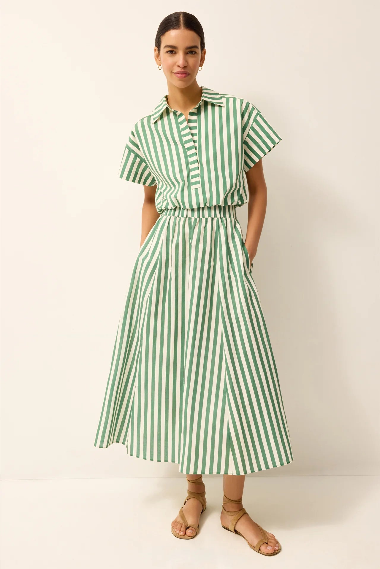 Woman wearing a green and white striped dress on a white background