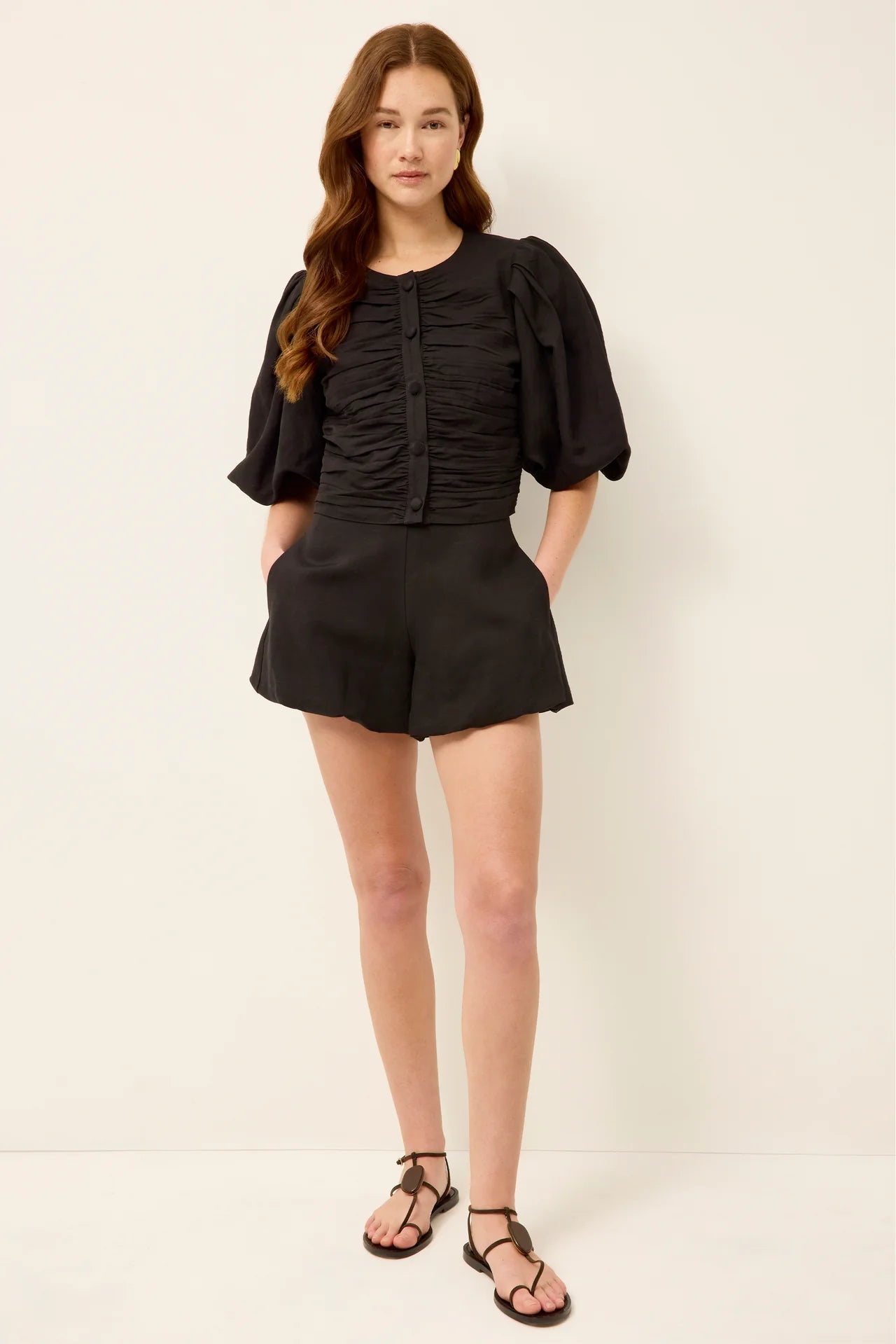 Woman wearing a black outfit with a top and shorts on a white background