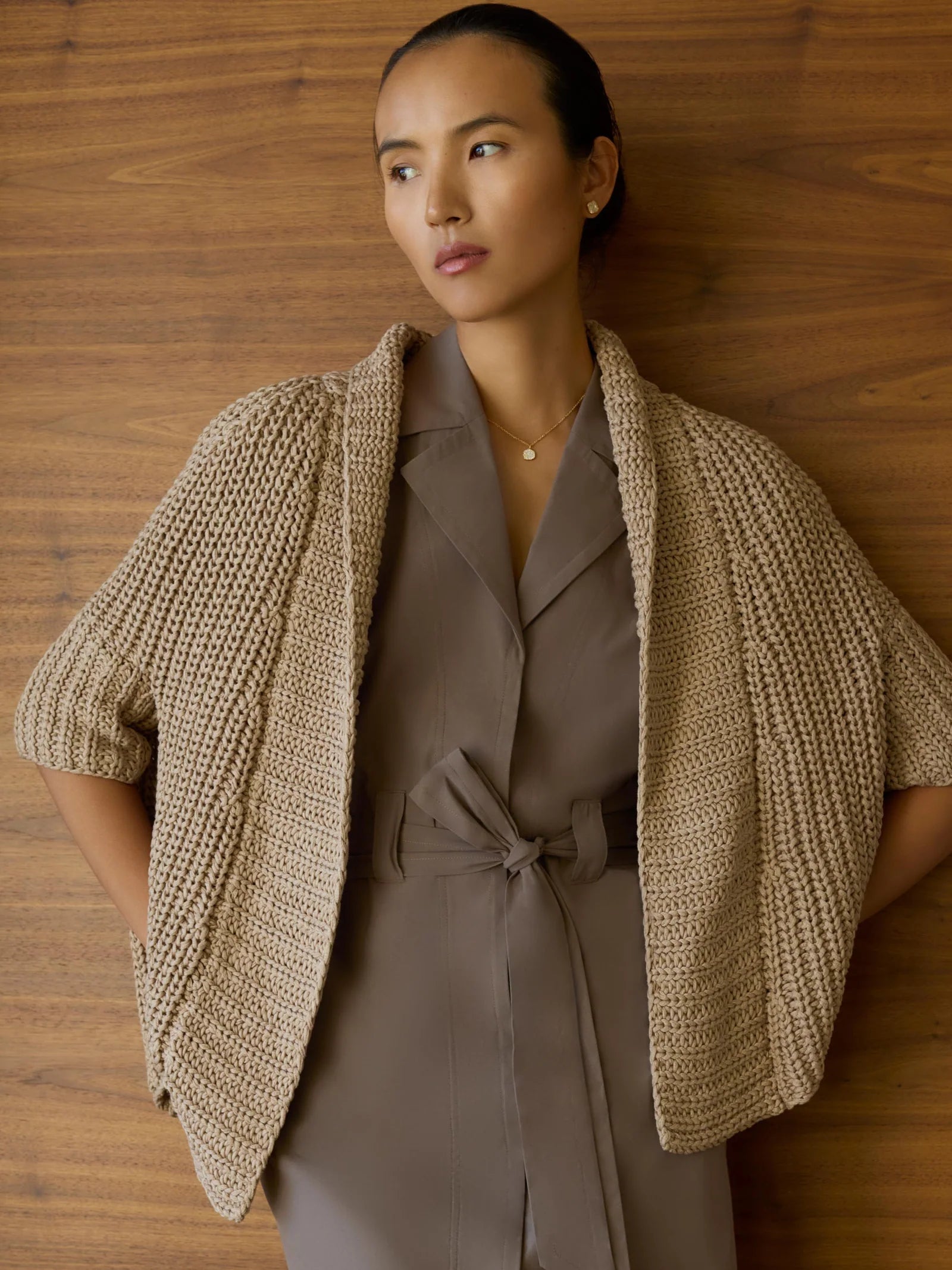 Woman wearing a brown outfit with a beige cardigan against a wooden background