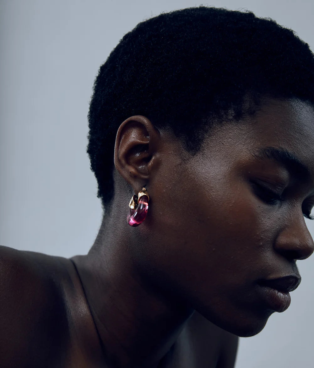 Close-up of a person wearing pink earrings with a neutral background