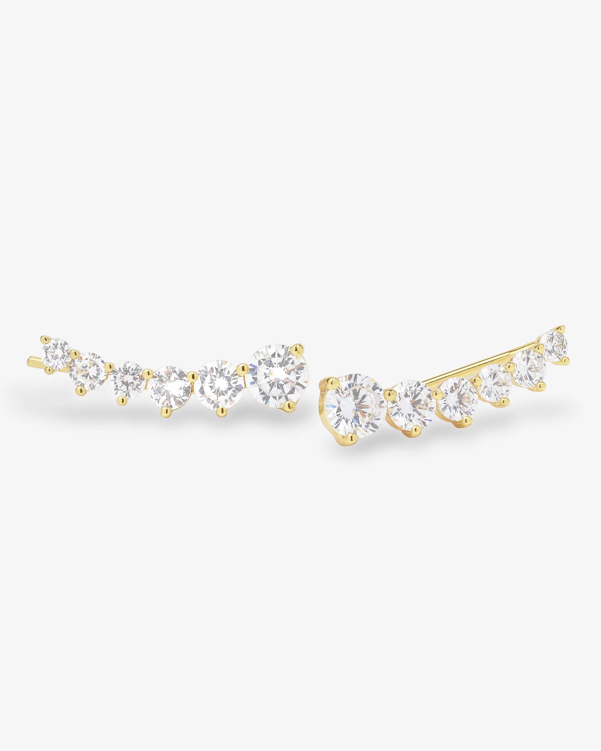 A pair of gold crescent-shaped stud earrings set with multiple round-cut clear gemstones, displayed on a clean white background.