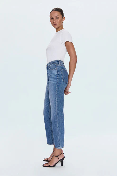 Woman wearing blue jeans and a white top on a light blue background