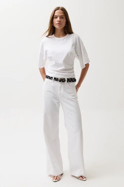 Woman wearing a white t-shirt and pants with a black belt on a white background
