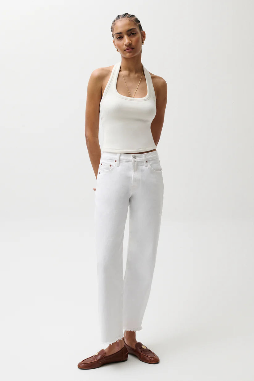 Woman wearing a white halter top and white pants on a plain background