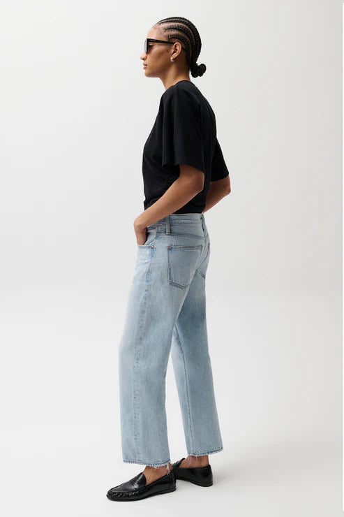 Person wearing a black t-shirt and light blue jeans on a white background