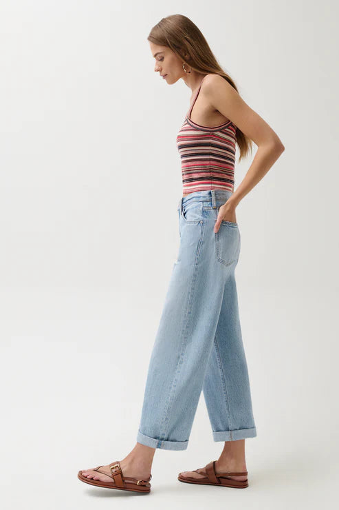 Woman wearing a striped tank top and light blue jeans on a white background