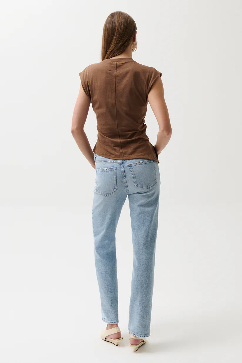 Person wearing a brown sleeveless top and light blue jeans on a white background
