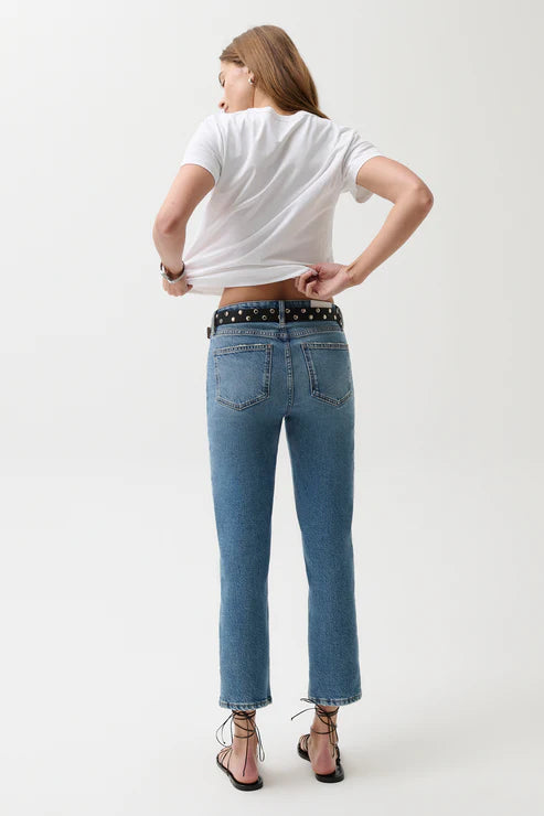 Person wearing a white t-shirt and blue jeans on a plain background