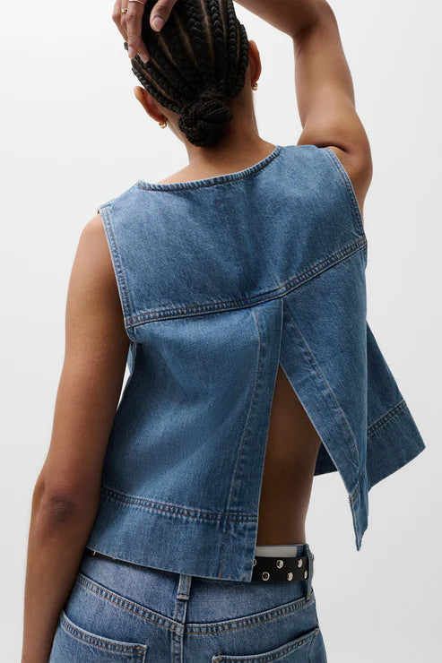 Person wearing a denim vest and pants on a plain background