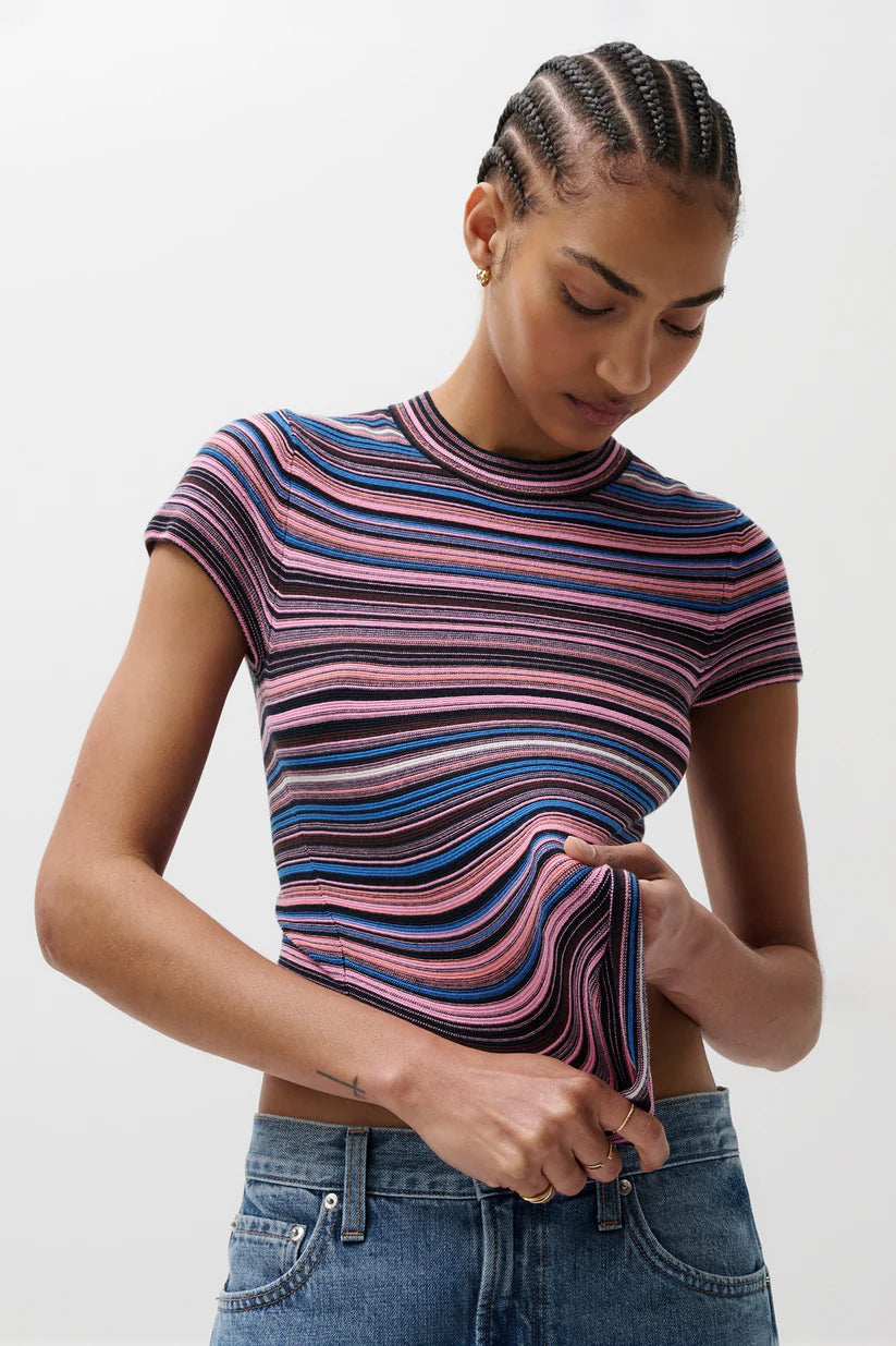 Woman wearing a colorful striped shirt and blue jeans on a white background