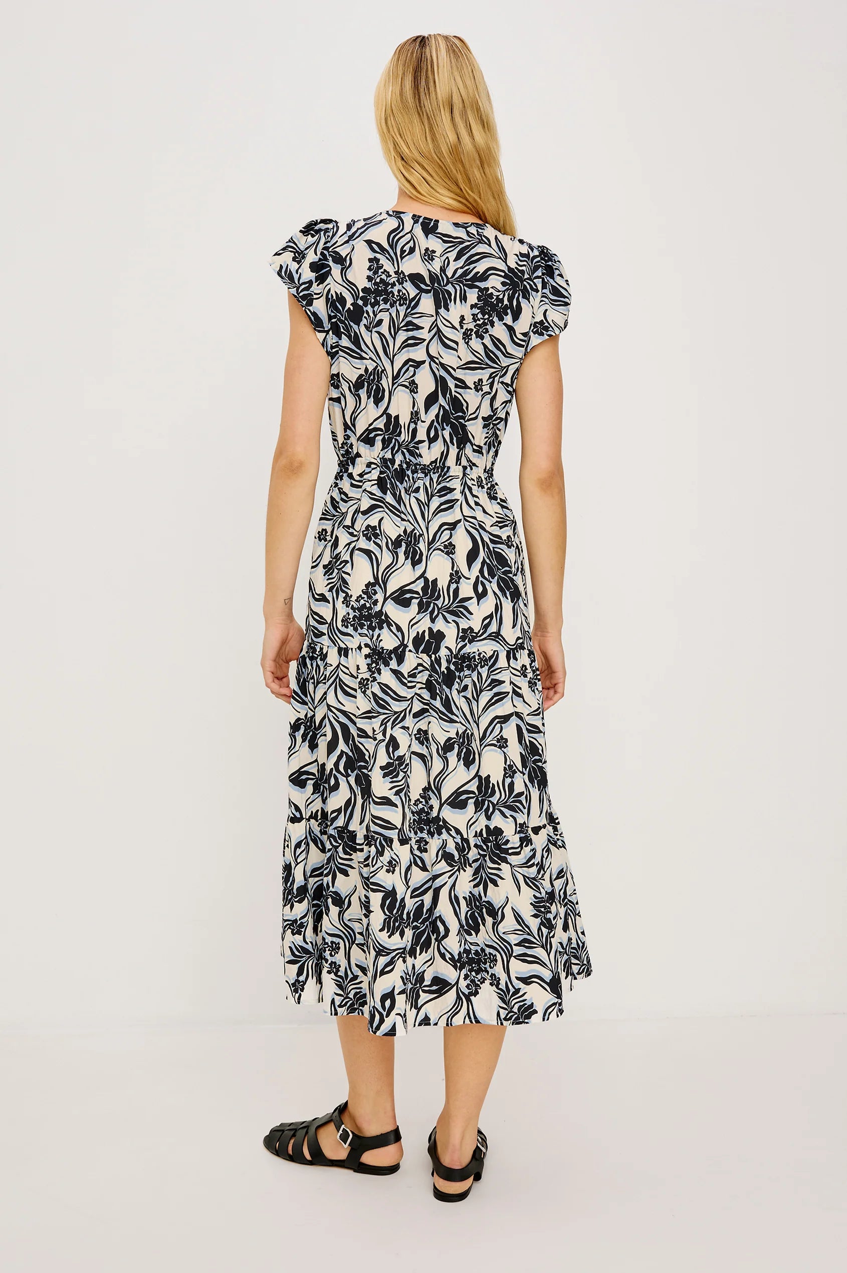 Woman wearing a black and white floral dress on a plain background