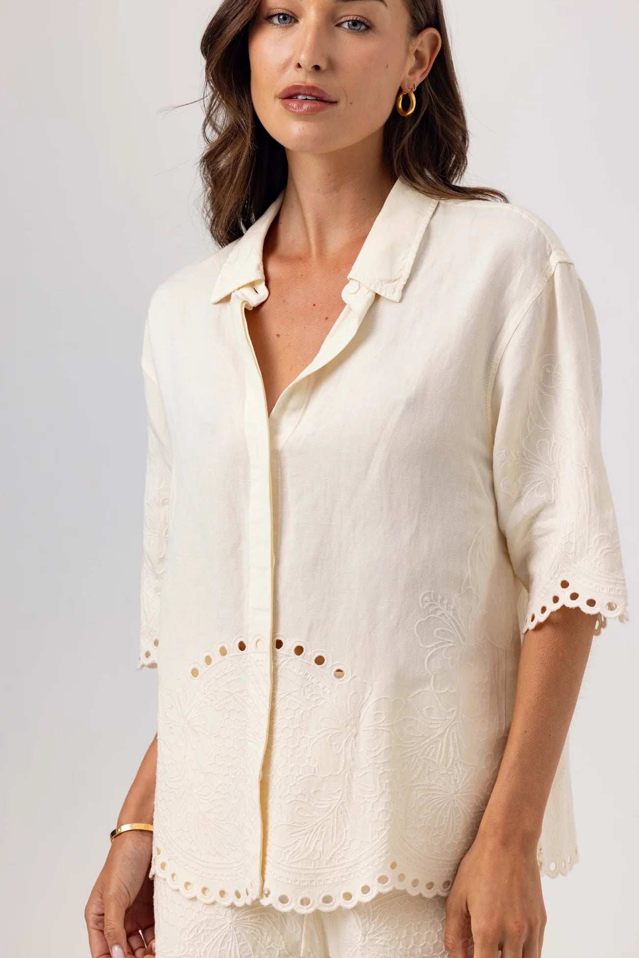 Woman wearing a white blouse with ruffled details on a plain background