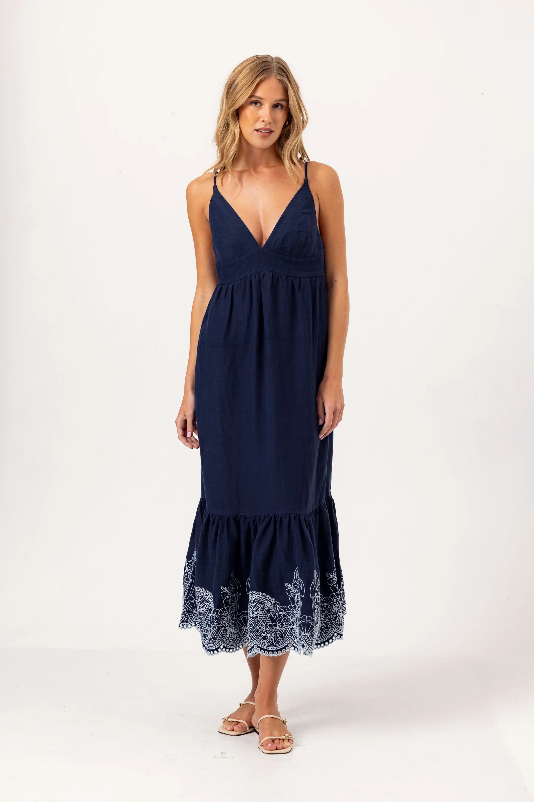 Woman wearing a navy blue dress with lace hem on a white background