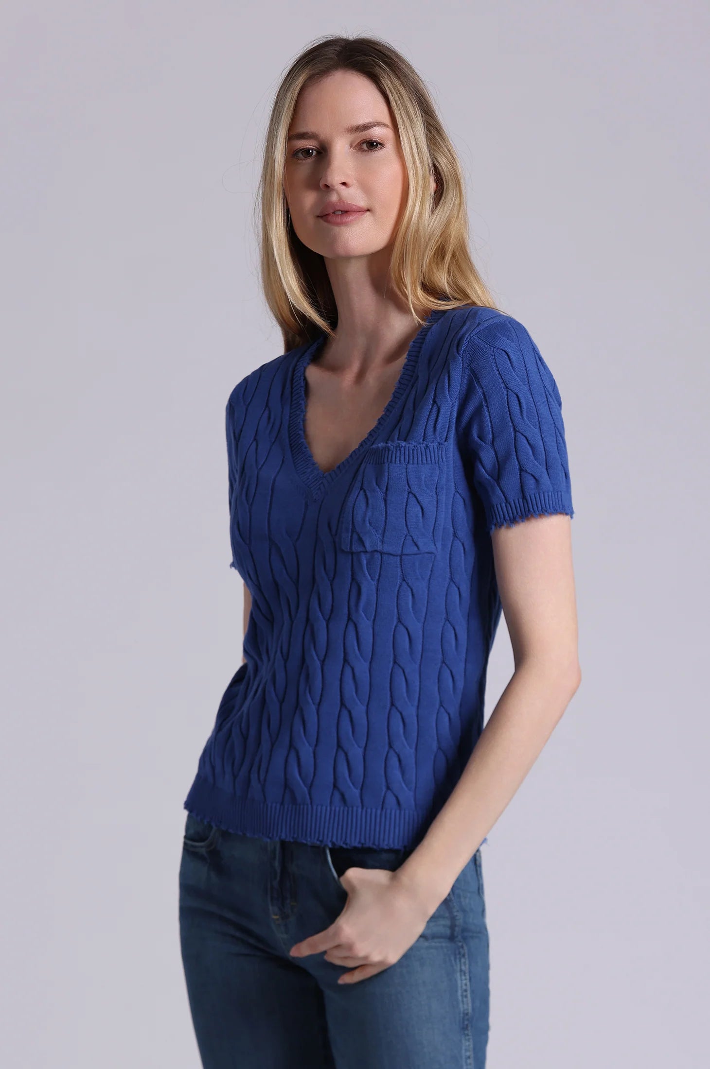Woman wearing a blue knitted top against a plain background