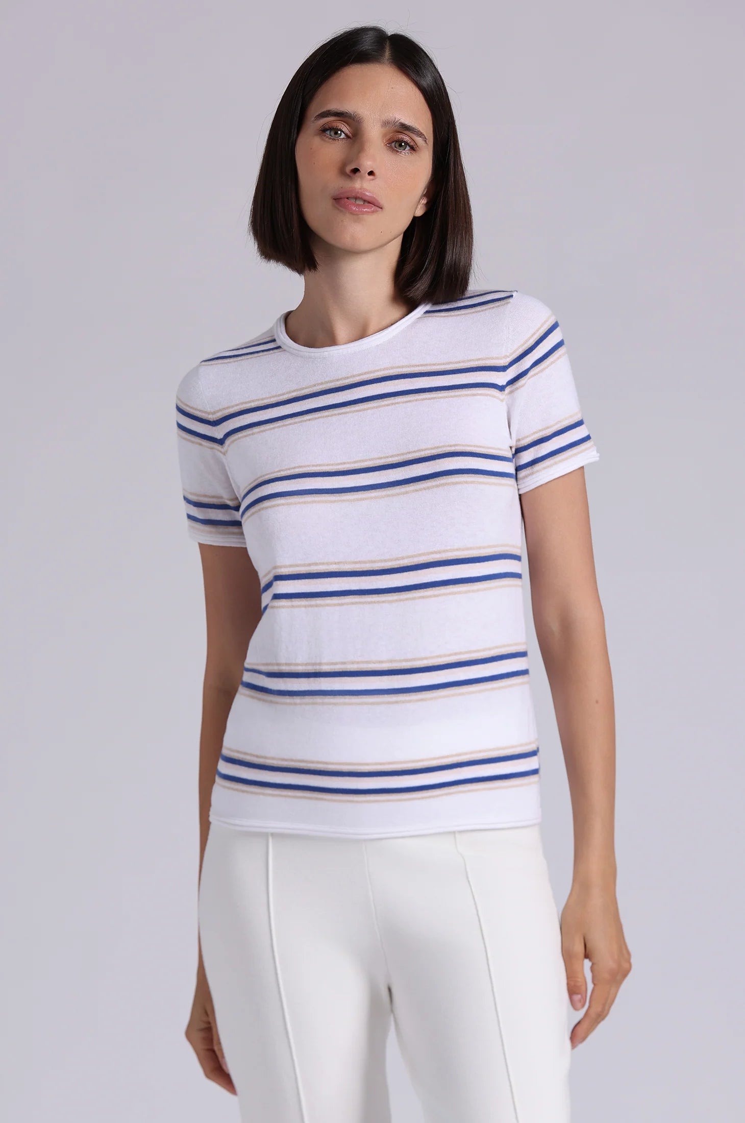 Woman wearing a white t-shirt with blue and gold stripes on a plain background
