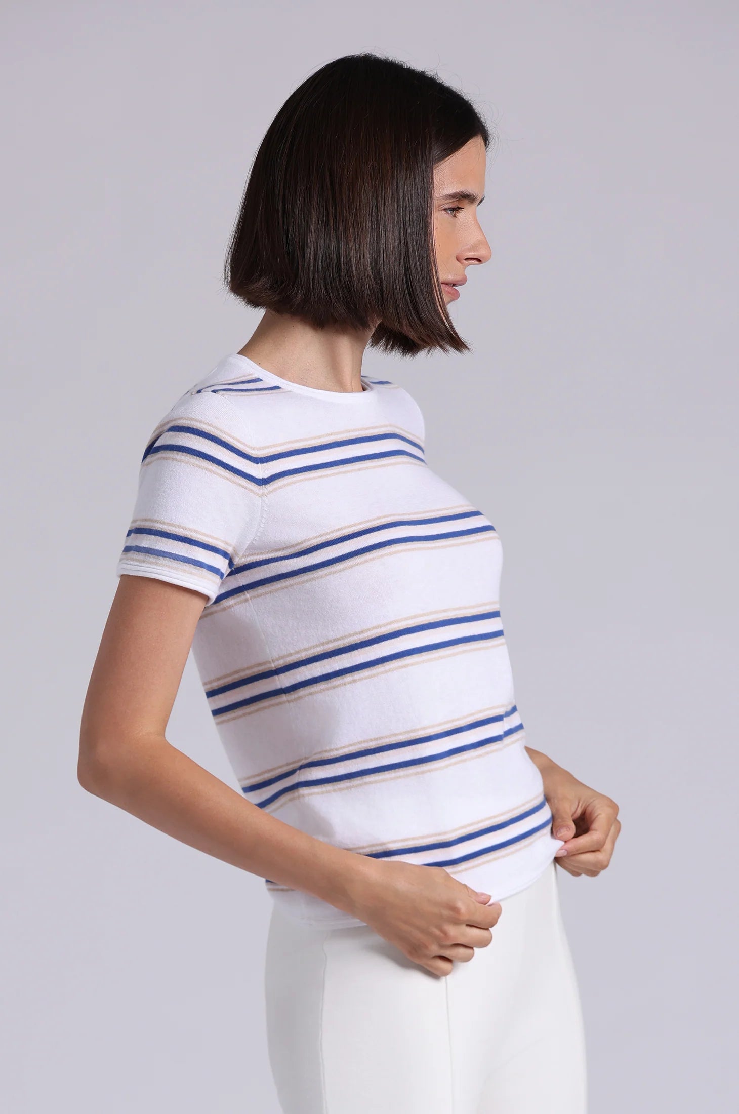 Woman wearing a white t-shirt with blue and yellow stripes on a gray background