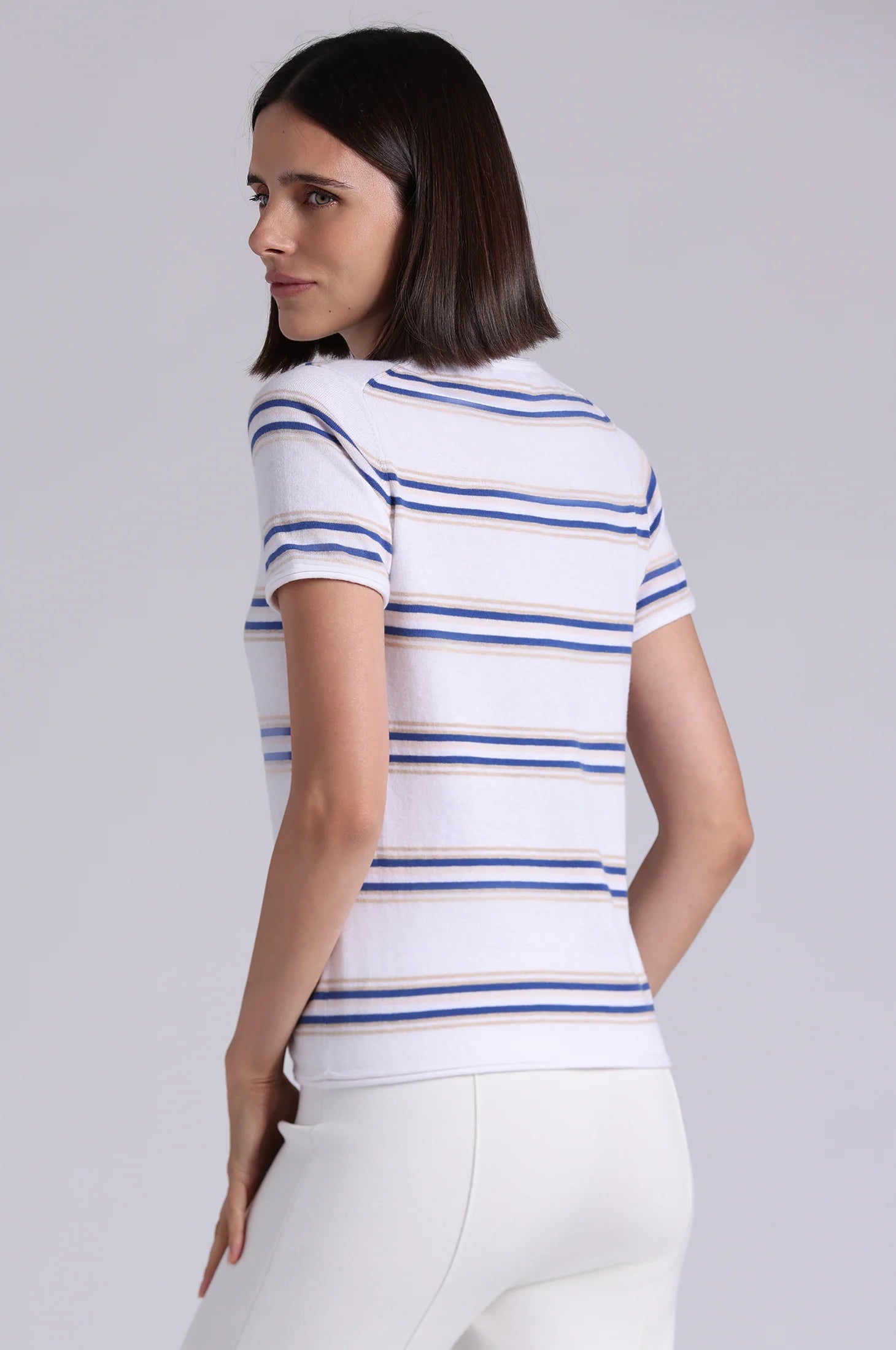 Woman wearing a white t-shirt with blue and gold stripes on a plain background