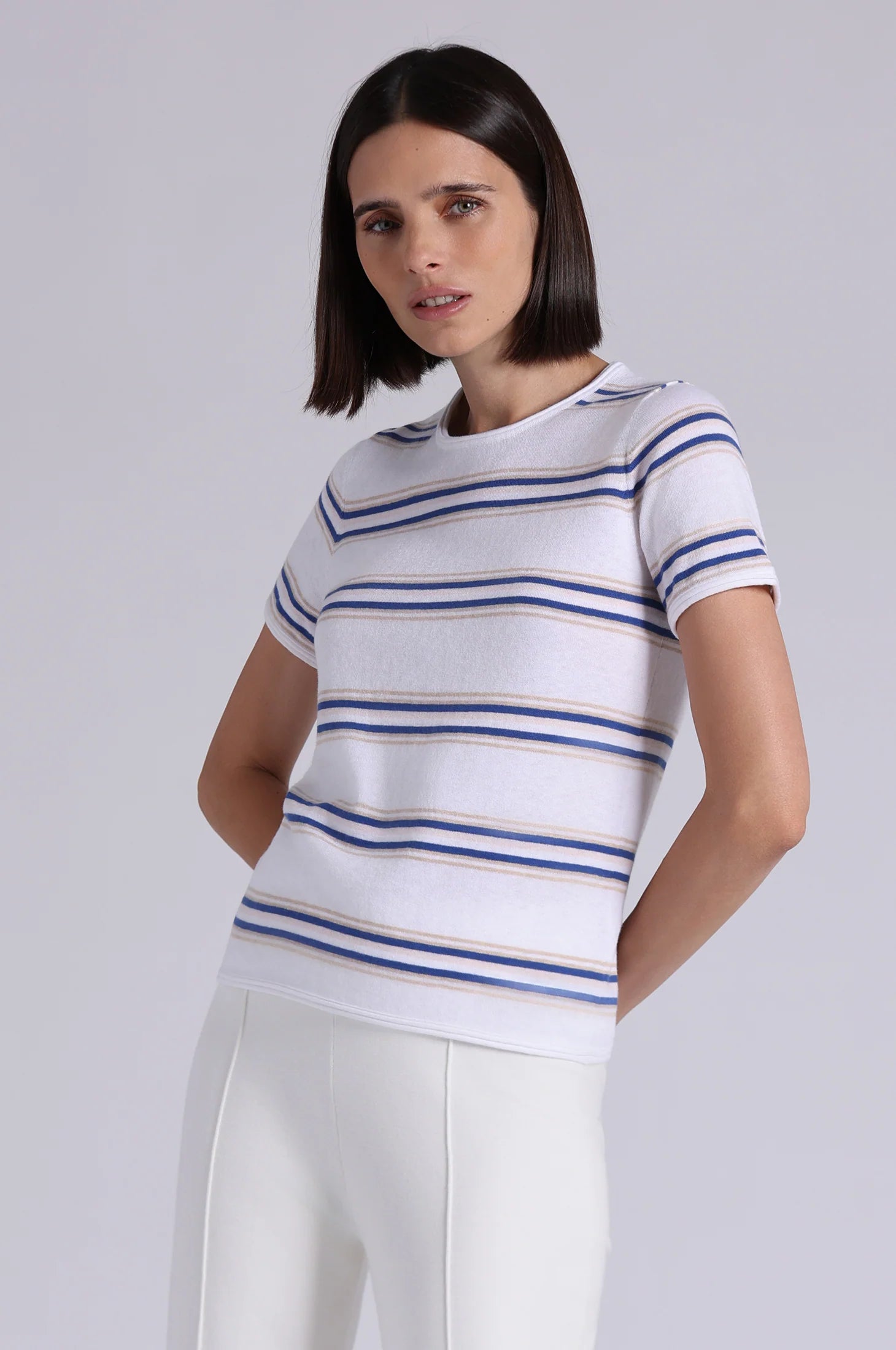 Woman wearing a white and blue striped shirt against a plain background