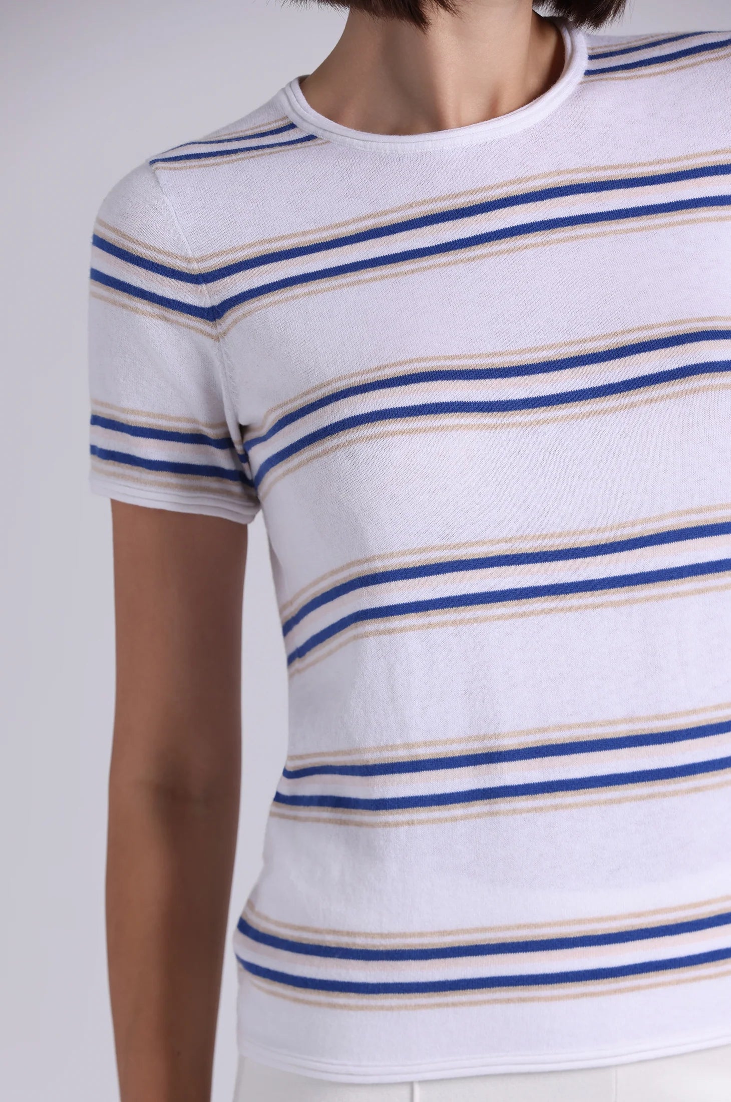 White t-shirt with blue and beige stripes on a plain background