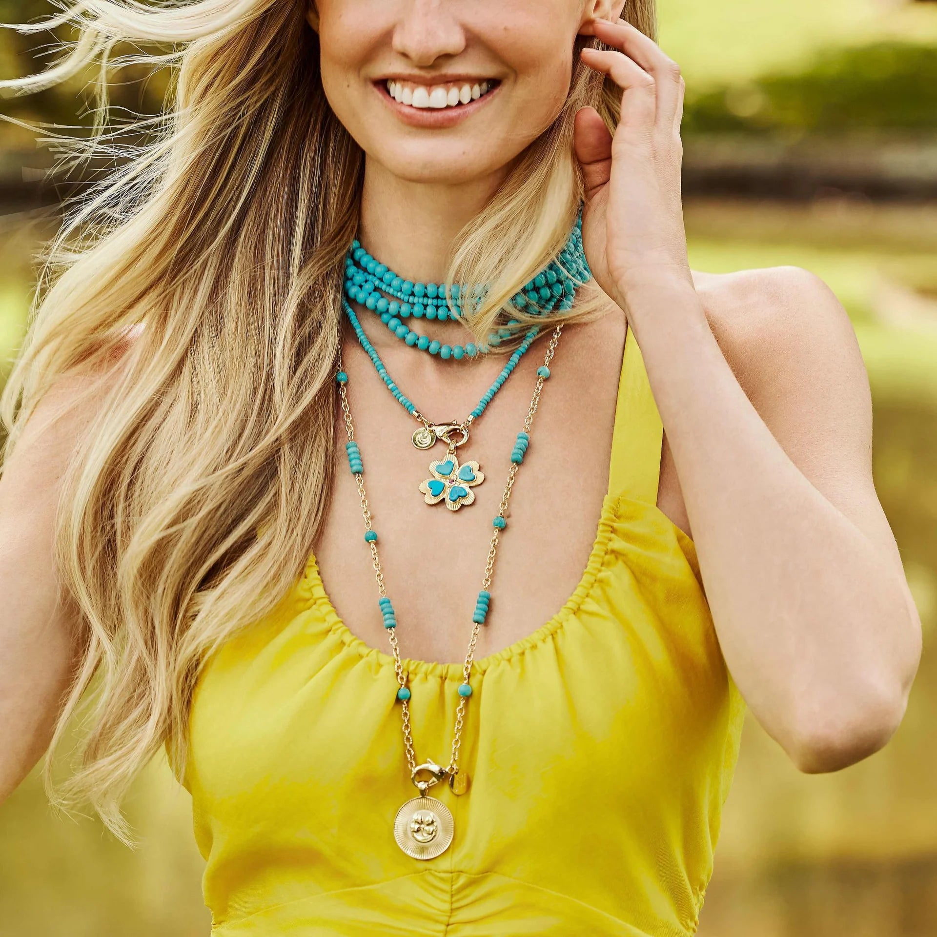 Woman wearing multiple necklaces with a blurred natural background
