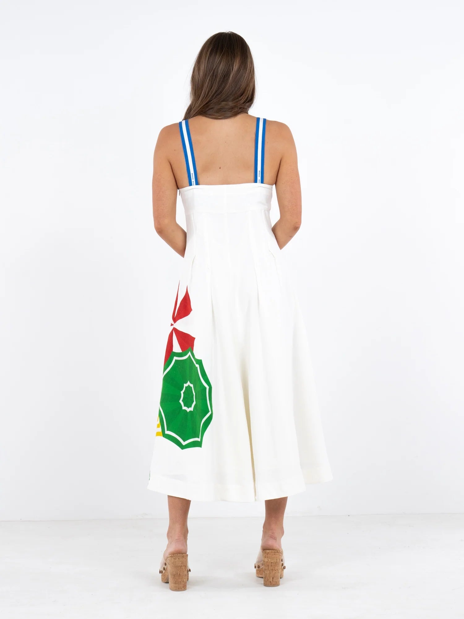 Woman wearing a white dress with a green and red design on a white background