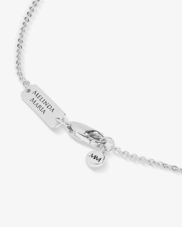 Silver necklace with engraved tag and heart-shaped charm on a white background