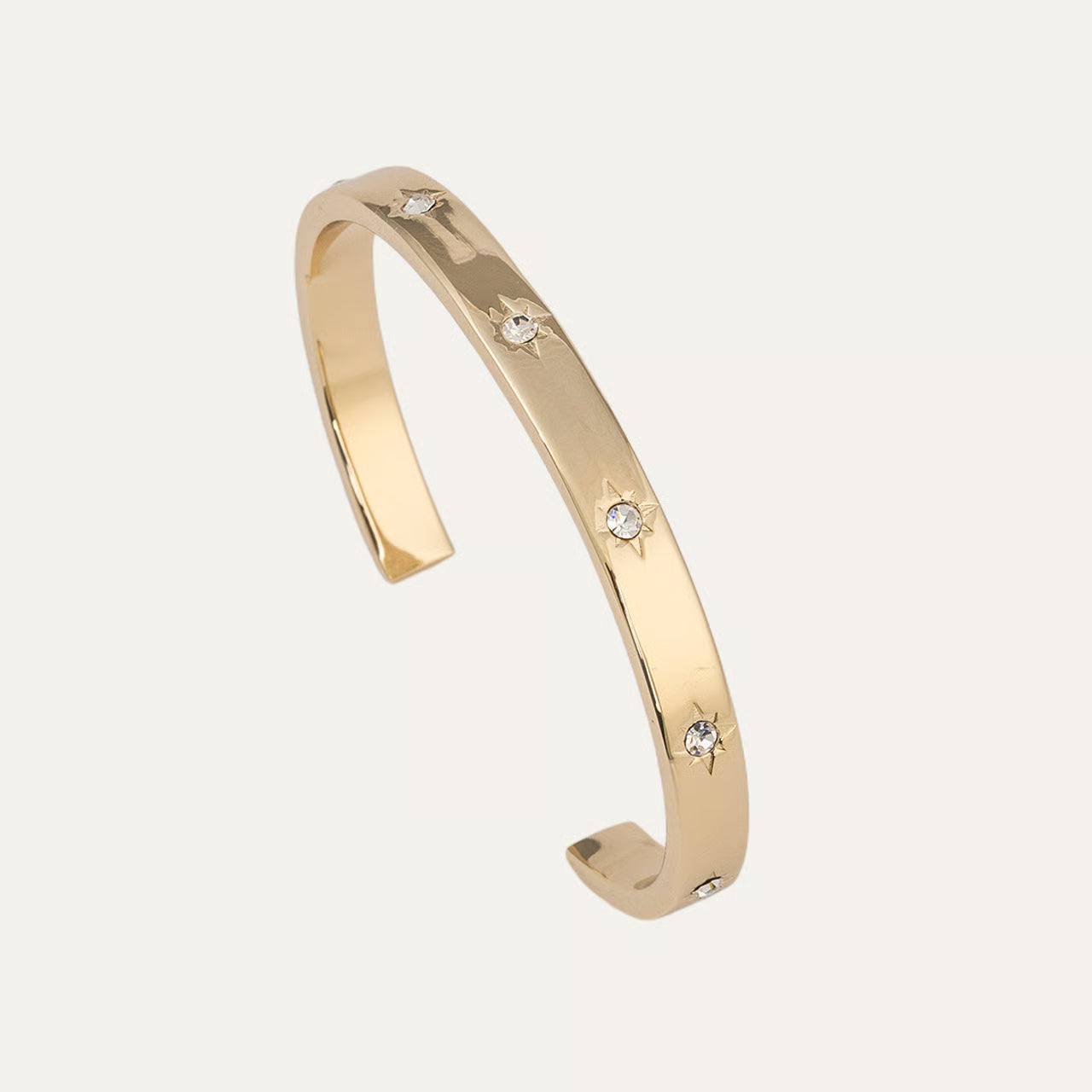 Gold bracelet with small diamonds on a light beige background