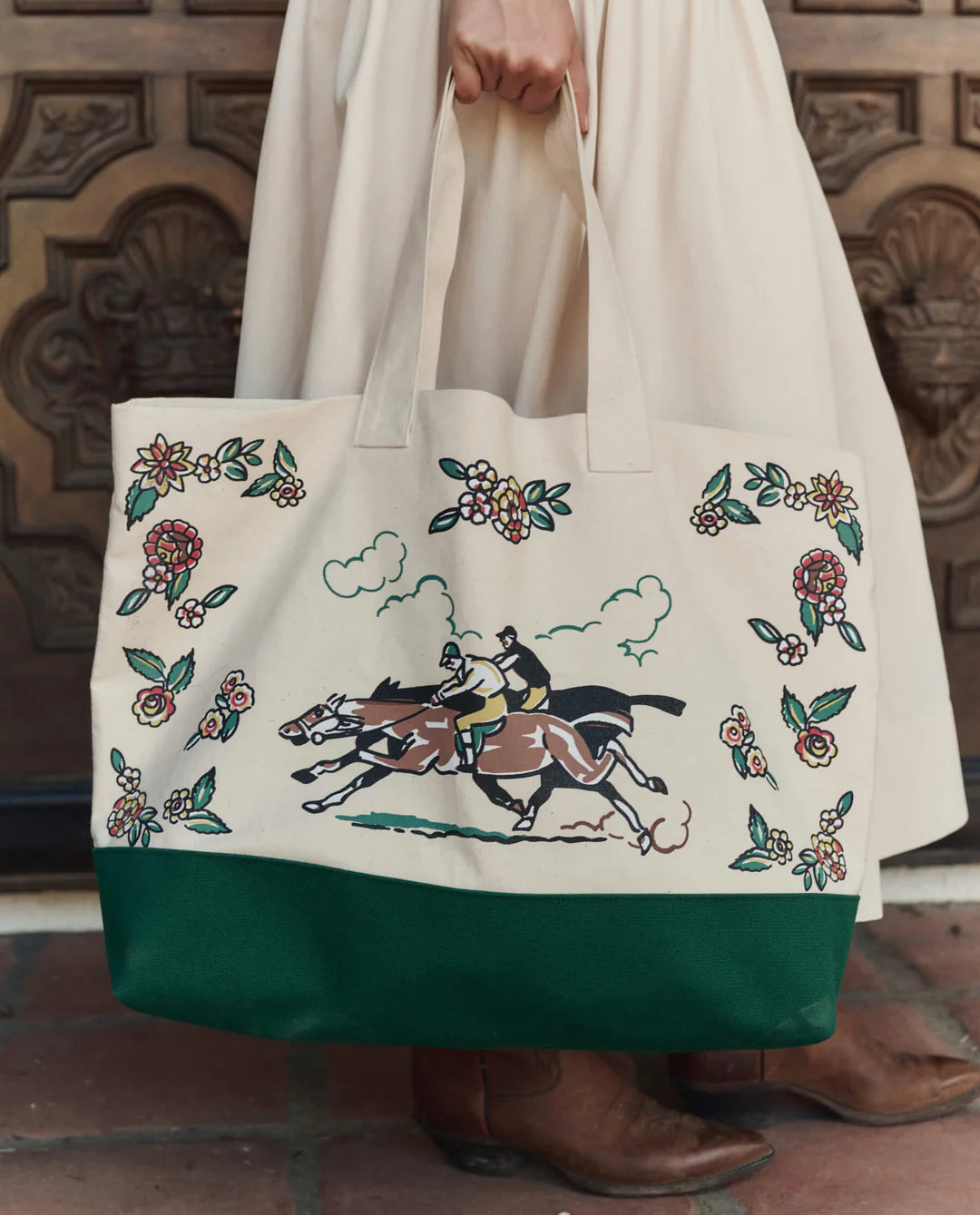 Tote bag with horse and floral design held by a person wearing a white coat.