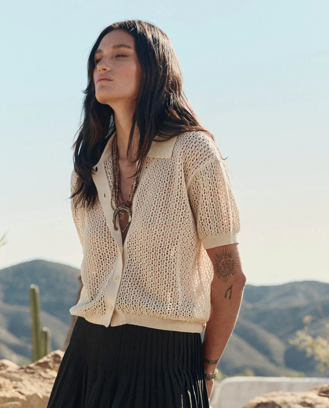 Woman wearing a beige knitted cardigan with a desert landscape in the background