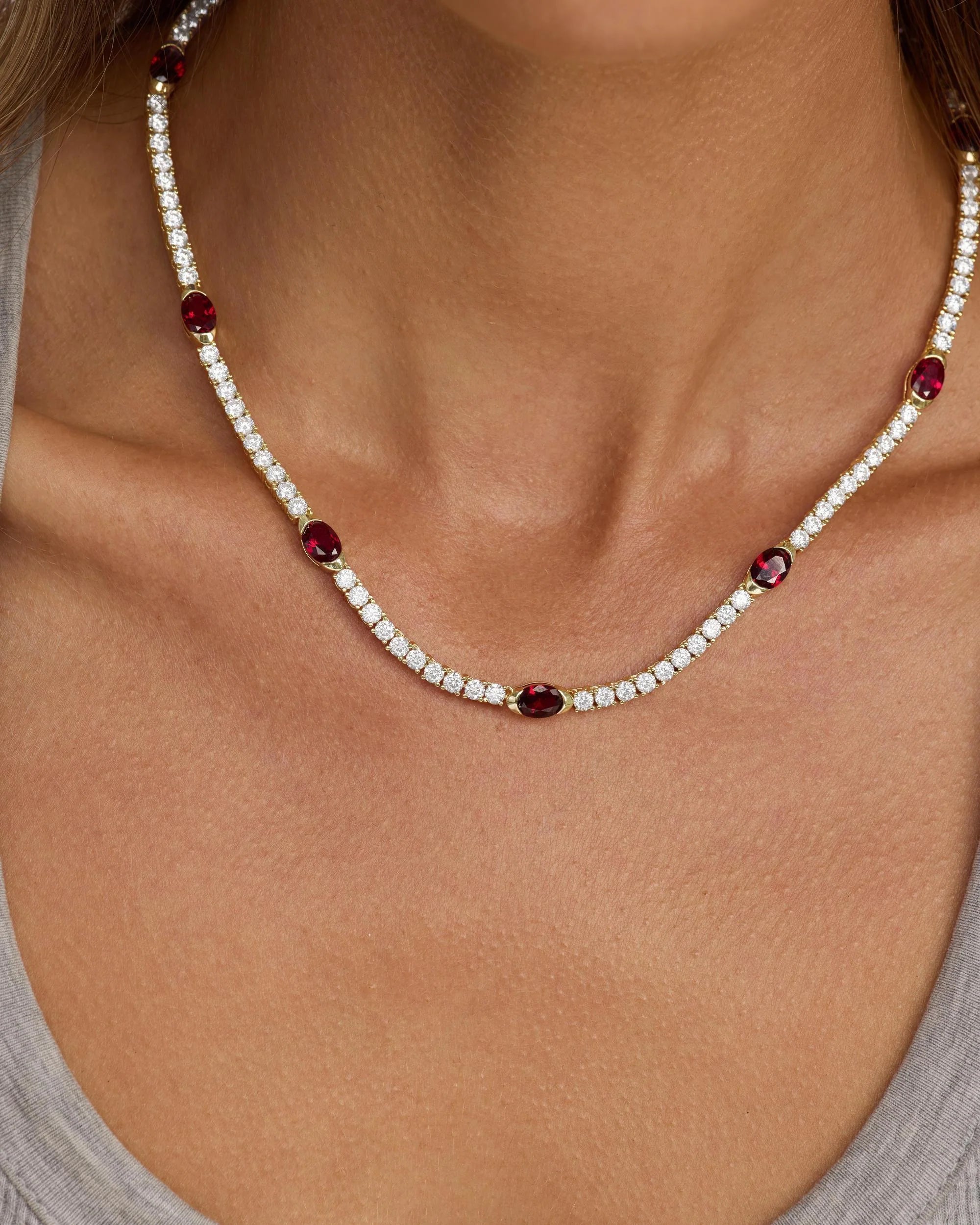 Necklace with red and clear beads on a person wearing a gray top
