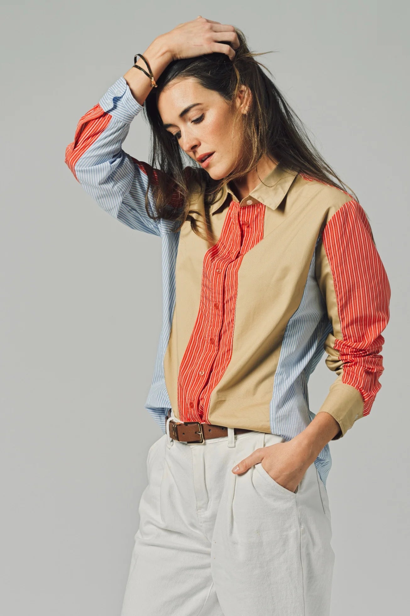 Woman wearing a beige vest over a red shirt with a gray background
