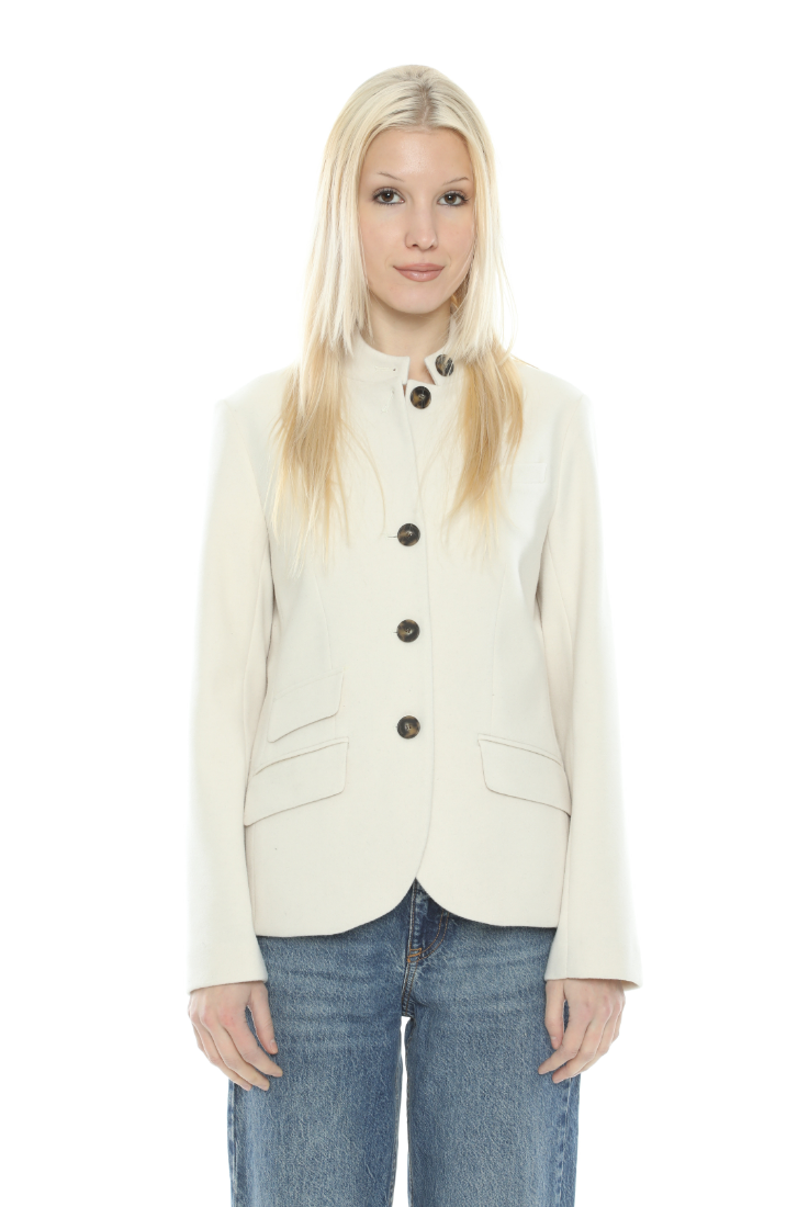 A blonde woman modeling a cream-colored, high-neck button-front blazer with dark buttons, paired with blue jeans, against a plain white background.