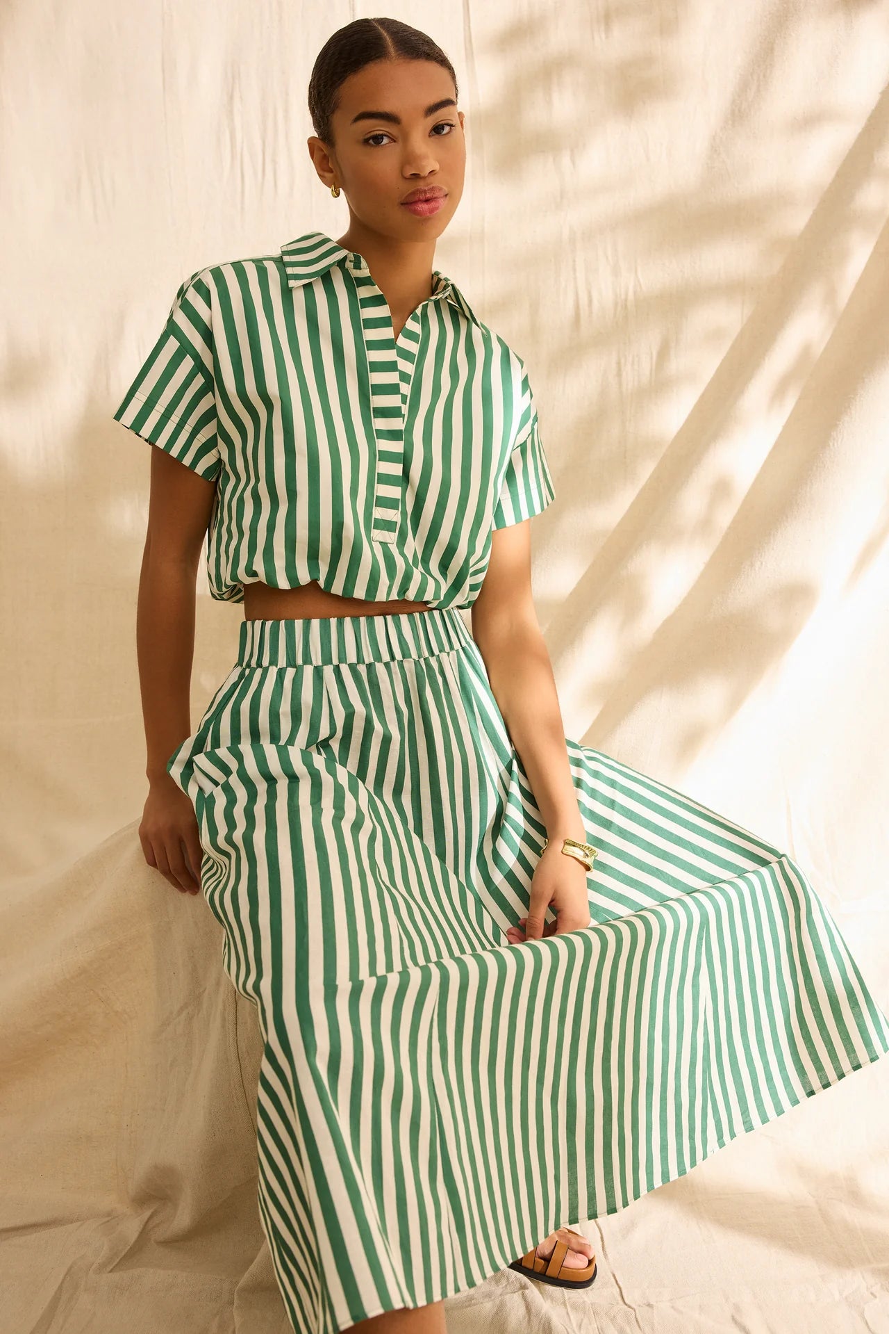 Woman wearing a green and white striped outfit against a neutral background
