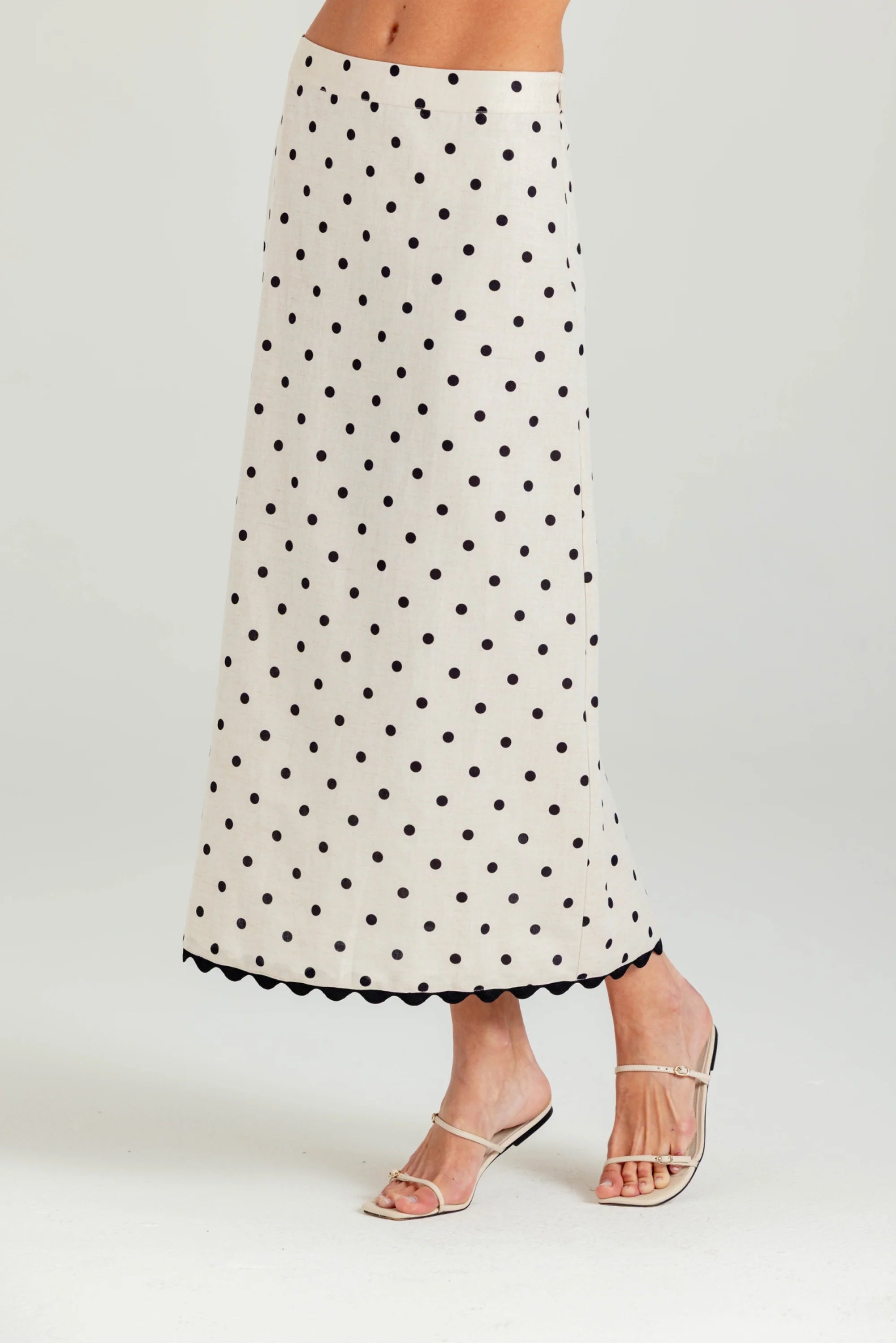 White skirt with black polka dots worn by a person on a white background