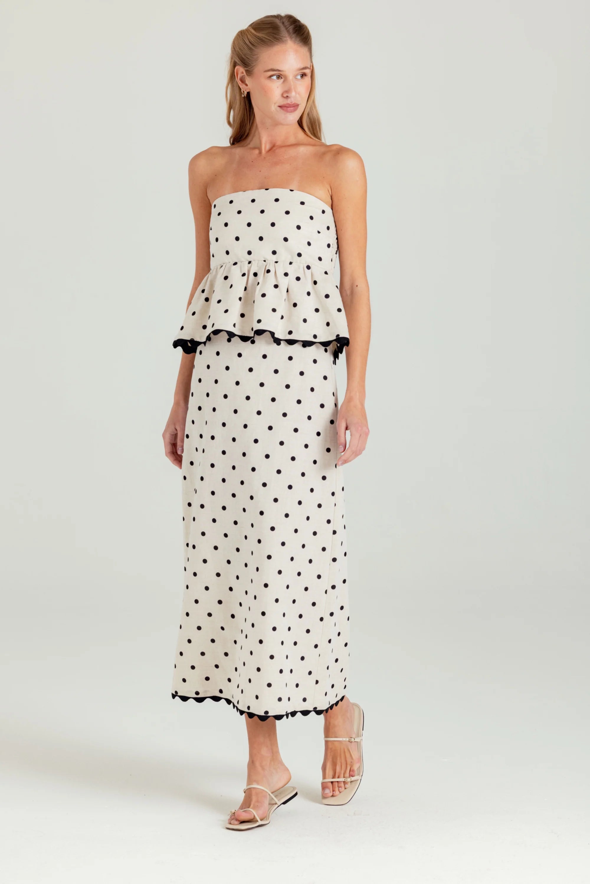 Woman wearing a strapless polka dot dress on a white background