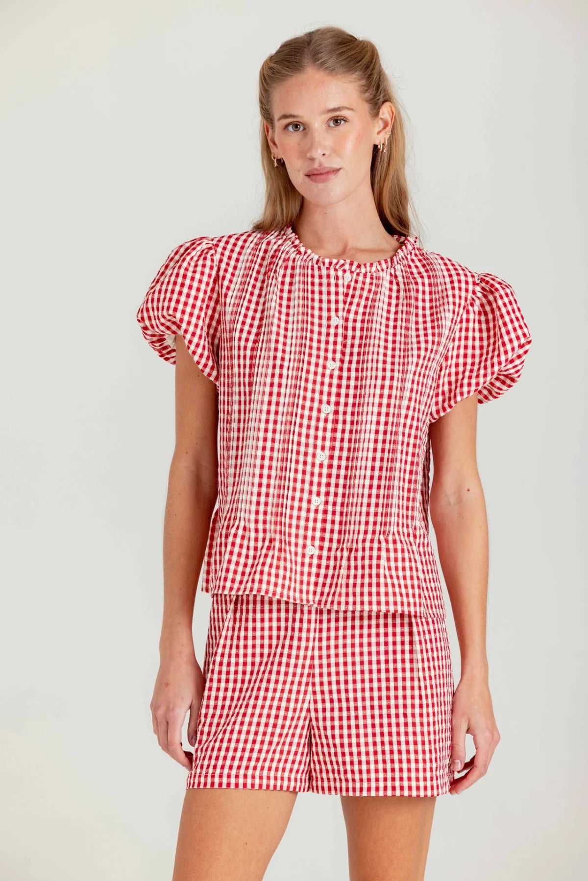 Woman wearing a red and white checkered dress against a plain background