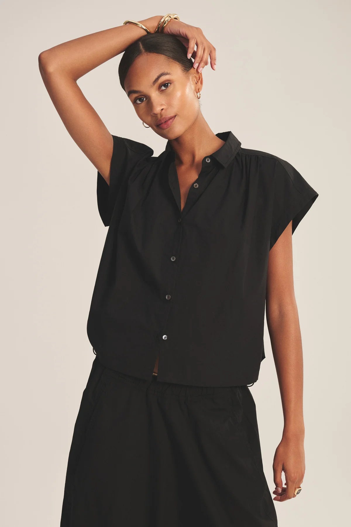 Woman wearing a black sleeveless blouse against a plain background