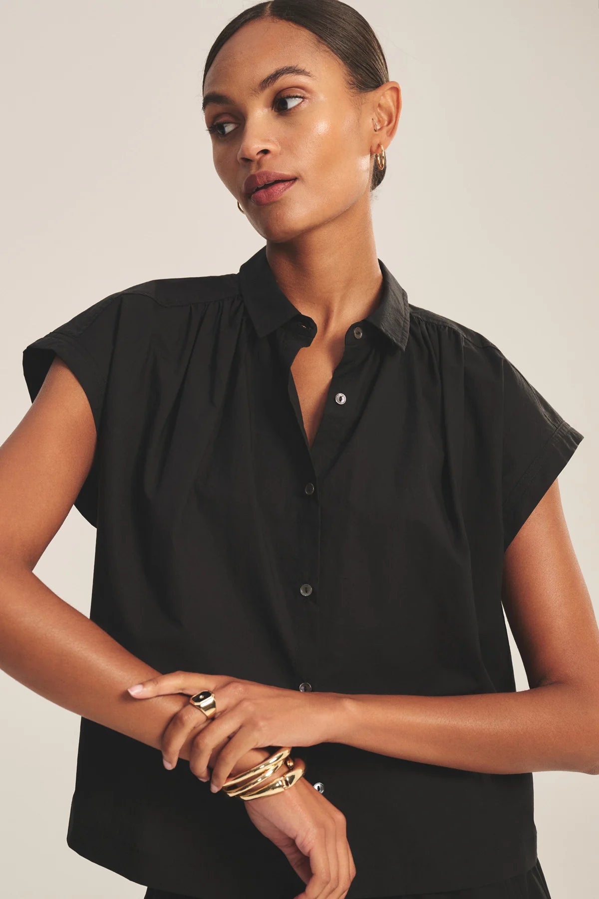 Woman wearing a black sleeveless blouse against a neutral background