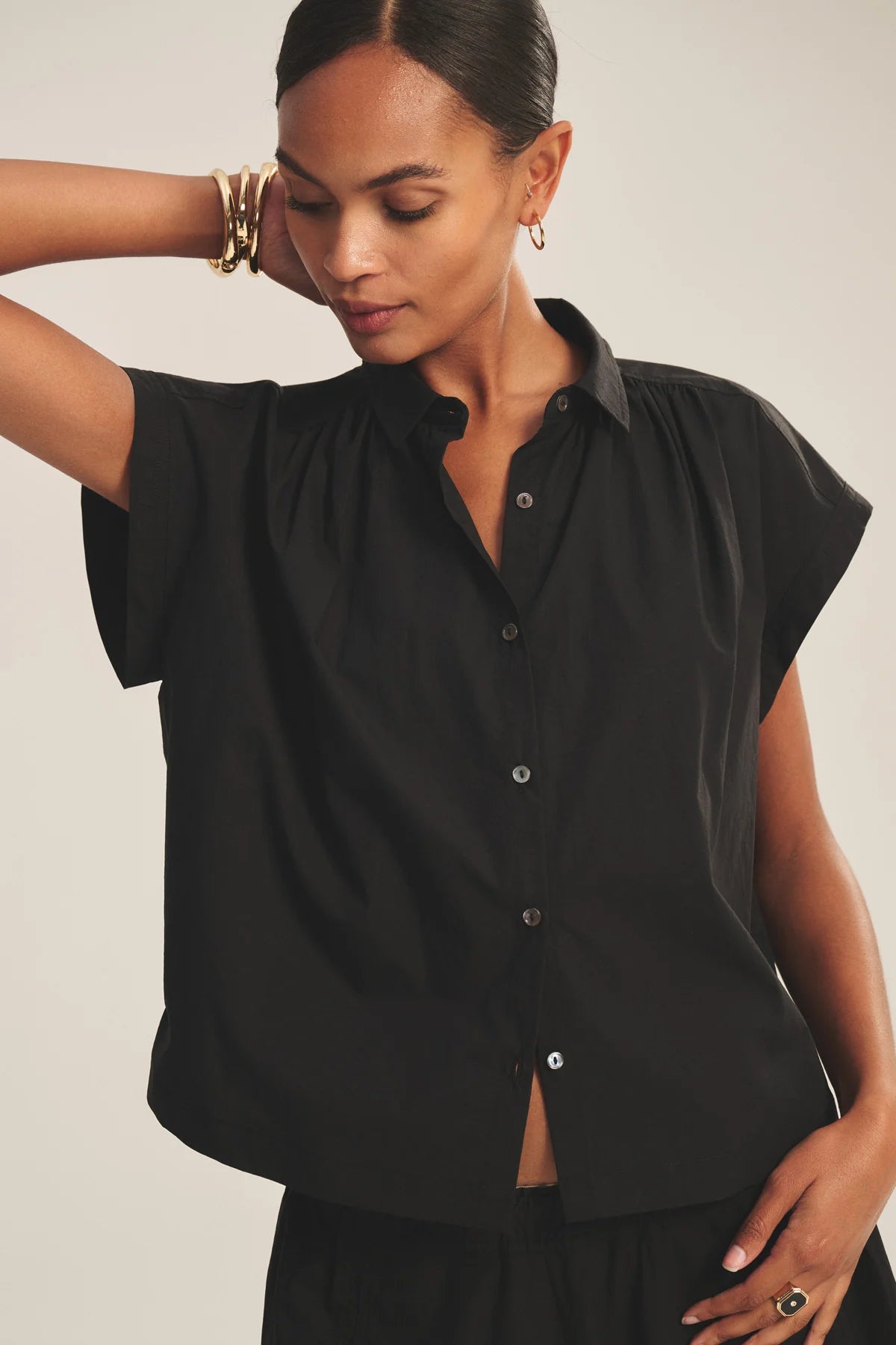 Woman wearing a black sleeveless blouse against a plain background