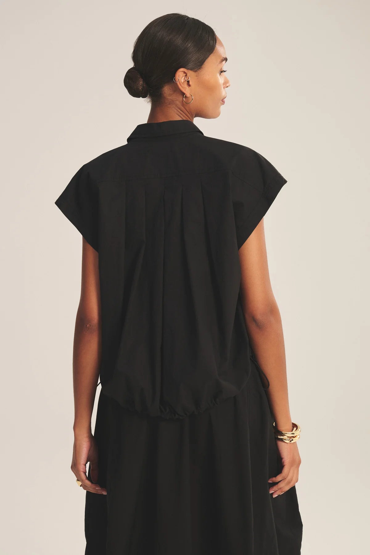 Woman wearing a black sleeveless dress against a plain background