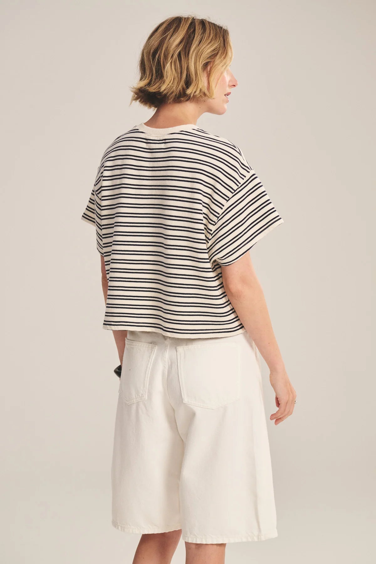 Person wearing a striped shirt and white shorts on a plain background
