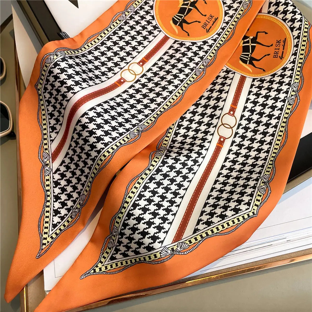 Decorative scarf with orange and black pattern on a surface