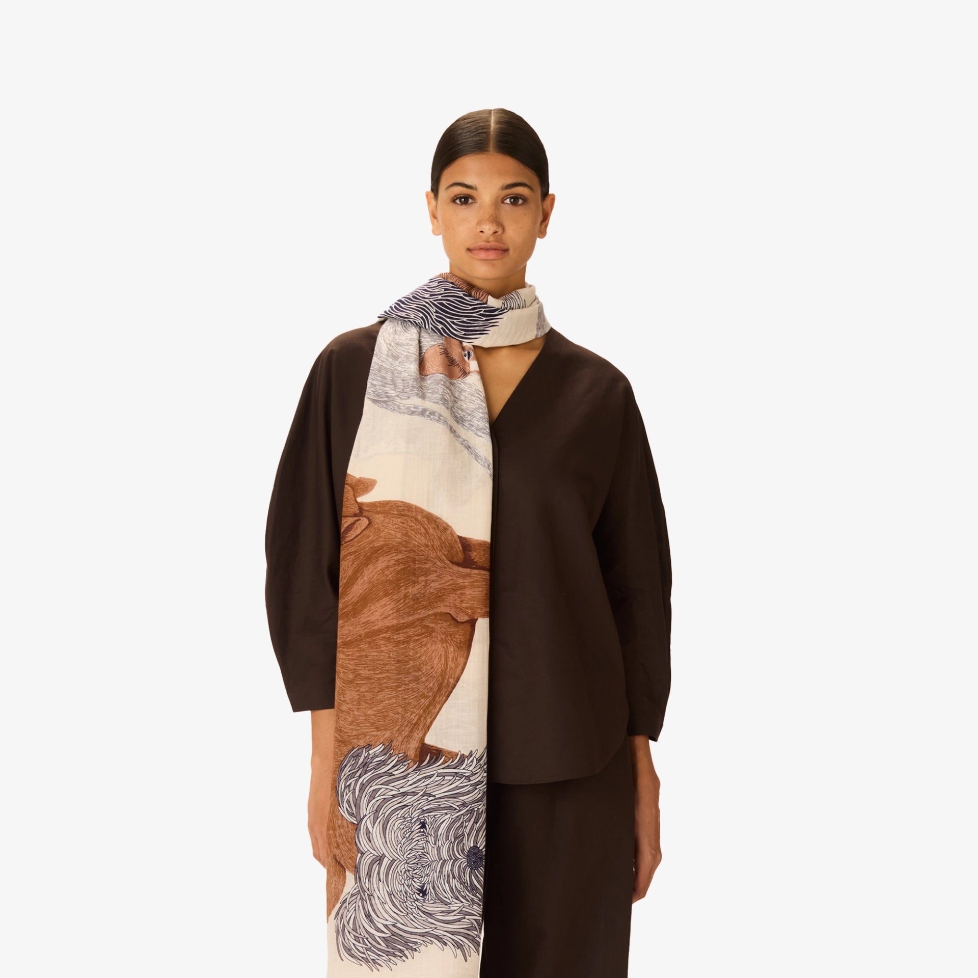 Woman wearing a long, patterned scarf with a neutral background