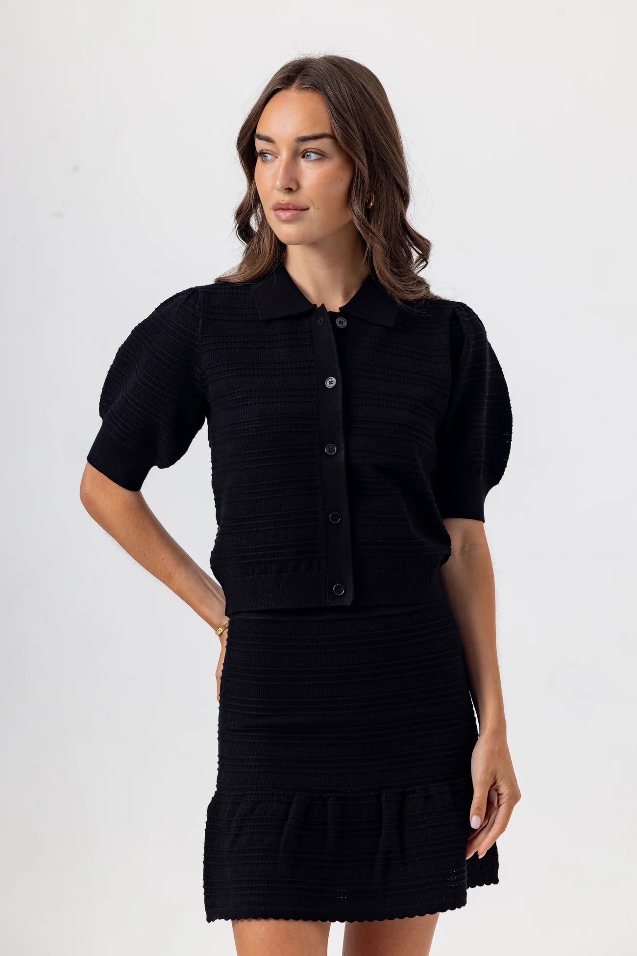 Woman wearing a black outfit with a textured pattern on a white background