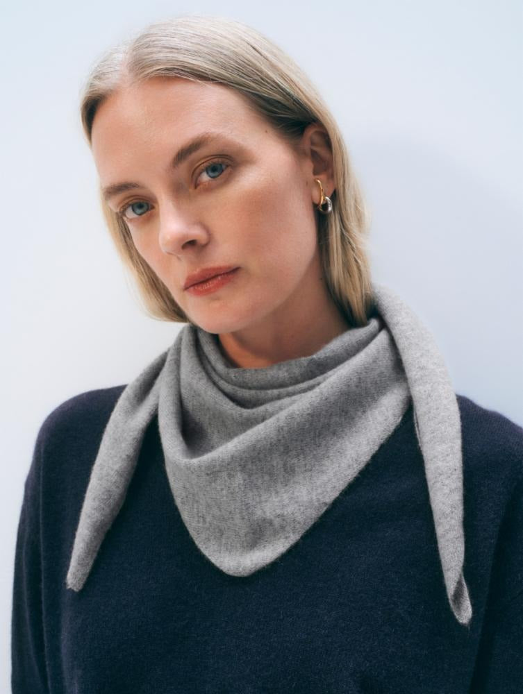Woman wearing a gray scarf against a light background