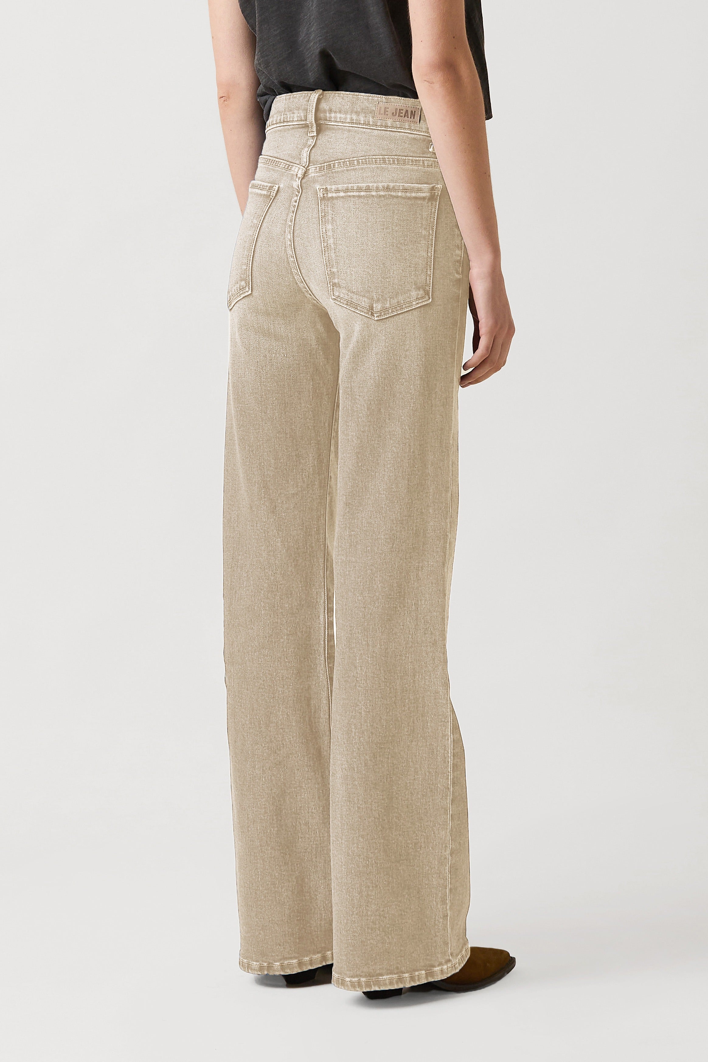 Beige wide-leg jeans worn by a person on a white background